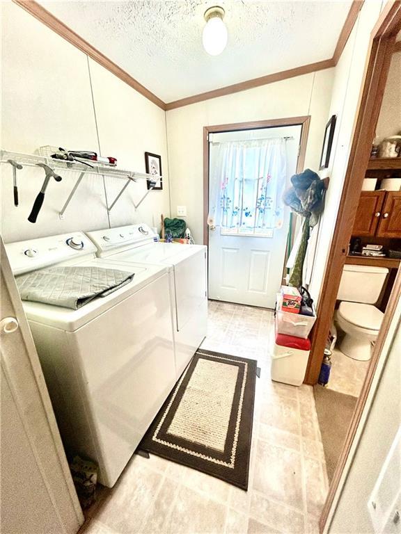 171 E 5th St, Schell City, MO 64783 - laundry room featuring a textured ceiling, washing machine and clothes dryer, ornamental molding, and laundry area