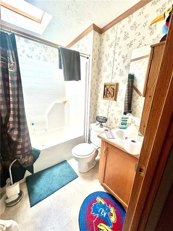 171 E 5th St, Schell City, MO 64783 - full bathroom with a skylight, wallpapered walls, toilet, vanity, and shower / tub combo
