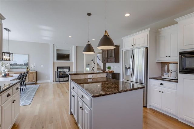 9500 N Lane Ave, Kansas City, MO 64157 - kitchen featuring black microwave, stainless steel fridge, light wood finished floors, a center island, and a tile fireplace