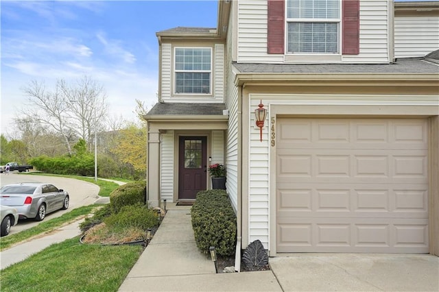 exterior space featuring an attached garage, driveway, and a shingled roof