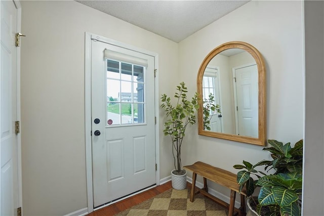 doorway featuring wood finished floors, baseboards, and a textured ceiling