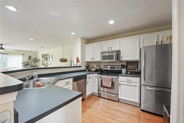 kitchen with dark countertops, white cabinetry, stainless steel appliances, and a sink