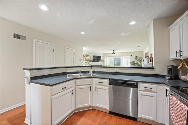 kitchen featuring light wood-style flooring, a sink, dark countertops, ceiling fan, and appliances with stainless steel finishes