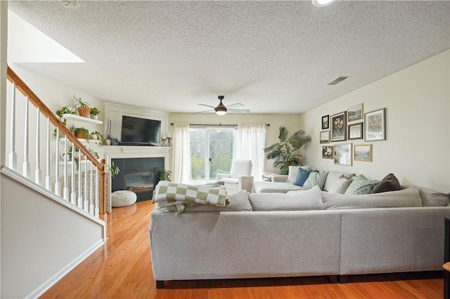 living area featuring stairway, ceiling fan, a textured ceiling, and visible vents