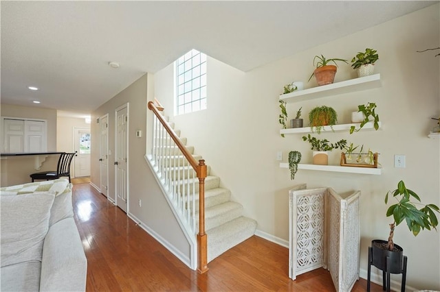 stairs with recessed lighting, wood finished floors, and baseboards
