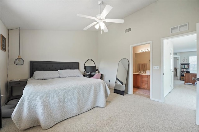 bedroom with vaulted ceiling, visible vents, light carpet, and connected bathroom