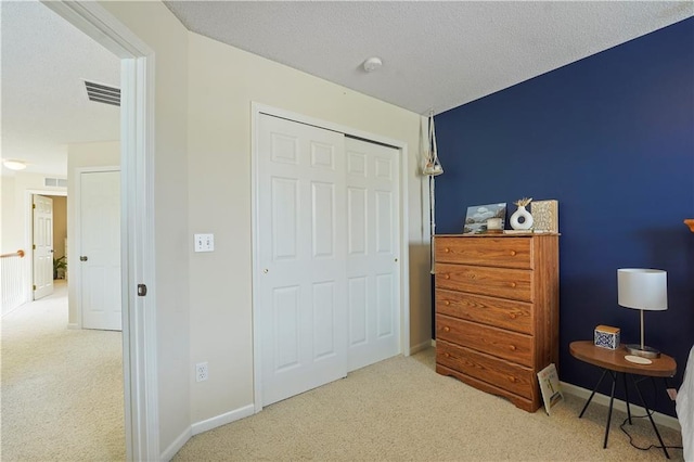 carpeted bedroom with baseboards, a textured ceiling, visible vents, and a closet