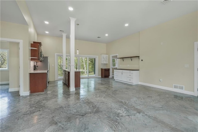 unfurnished living room with recessed lighting, visible vents, baseboards, decorative columns, and concrete floors