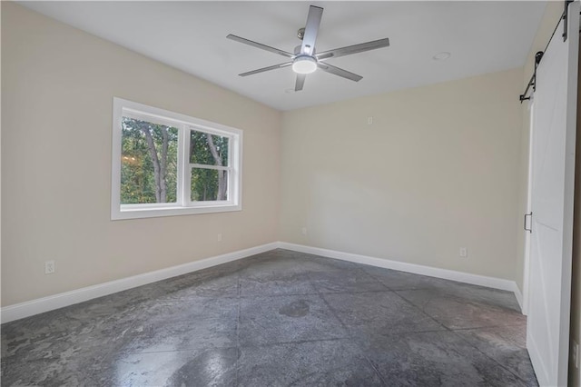 unfurnished room with a barn door, concrete flooring, a ceiling fan, and baseboards