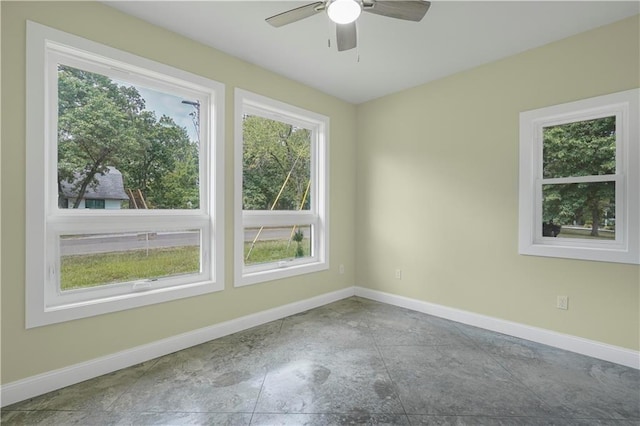 unfurnished room with plenty of natural light, a ceiling fan, and baseboards