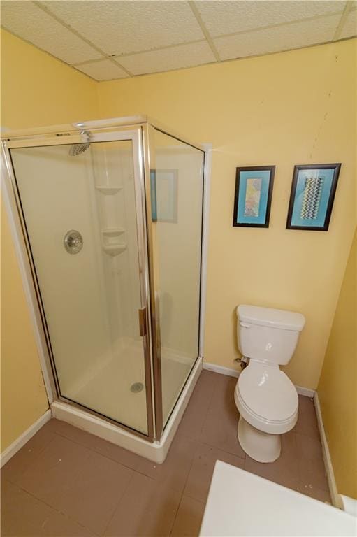 603 N 5th St, Atchison, KS 66002 - bathroom with a shower stall, toilet, baseboards, tile patterned flooring, and a paneled ceiling
