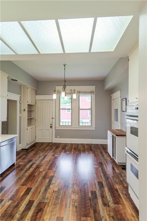 603 N 5th St, Atchison, KS 66002 - kitchen with double oven, dark wood-type flooring, stainless steel dishwasher, baseboards, and white cabinetry