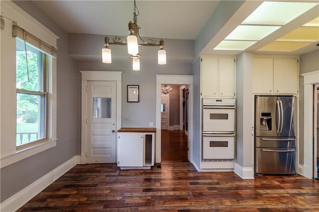 603 N 5th St, Atchison, KS 66002 - kitchen with stainless steel fridge, white double oven, a chandelier, dark wood-type flooring, and baseboards