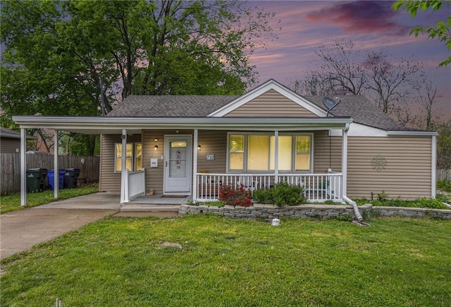 view of front facade featuring a porch, fence, a shingled roof, and a front yard
