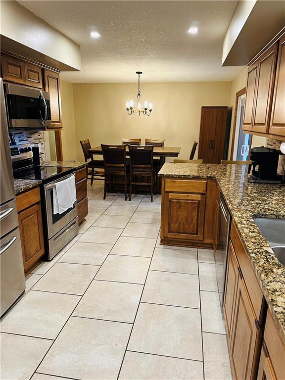 kitchen with stainless steel appliances, a notable chandelier, recessed lighting, and a peninsula