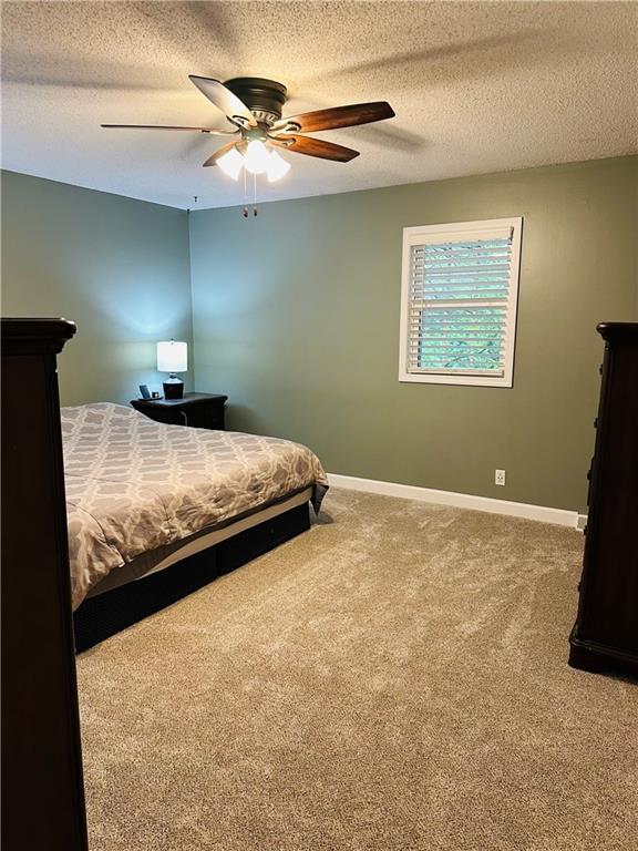 carpeted bedroom featuring a ceiling fan, a textured ceiling, and baseboards