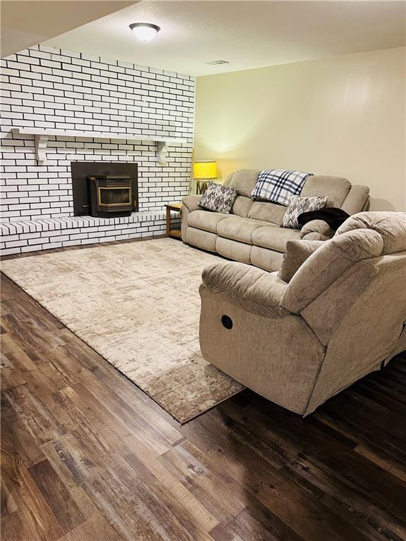 living area with visible vents, wood finished floors, and a fireplace