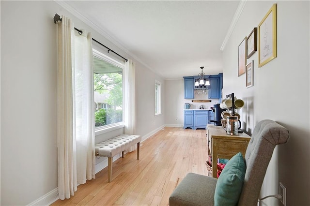 interior space with an inviting chandelier, baseboards, ornamental molding, and light wood finished floors