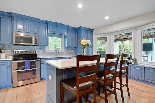 kitchen featuring light countertops, a breakfast bar, stainless steel appliances, and blue cabinets