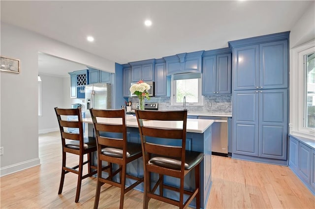 kitchen featuring a kitchen island, a breakfast bar area, light countertops, blue cabinets, and appliances with stainless steel finishes