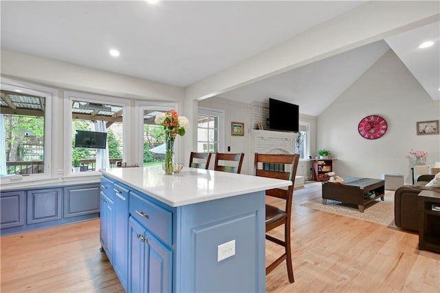 kitchen featuring a breakfast bar, a fireplace, light wood-style floors, open floor plan, and blue cabinets