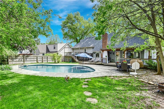 view of swimming pool with a lawn, a fenced in pool, a wooden deck, and a fenced backyard