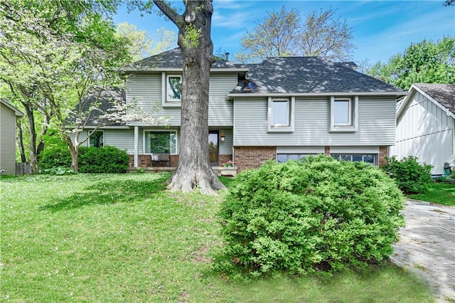 view of front of house with brick siding, a shingled roof, and a front lawn