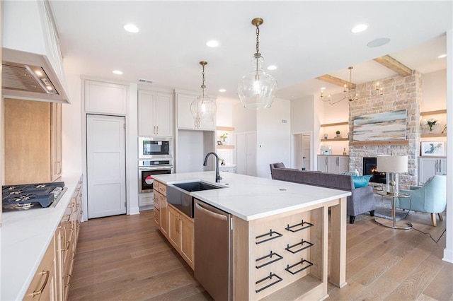 2315 SW Serena Pl, Lees Summit, MO 64082 - kitchen featuring stainless steel appliances, wood finished floors, custom range hood, light countertops, and a center island with sink