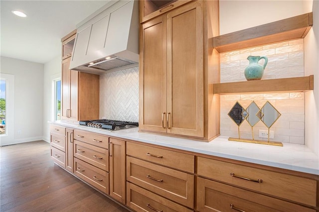 2315 SW Serena Pl, Lees Summit, MO 64082 - kitchen featuring custom exhaust hood, tasteful backsplash, dark wood-type flooring, stainless steel gas cooktop, and light stone countertops