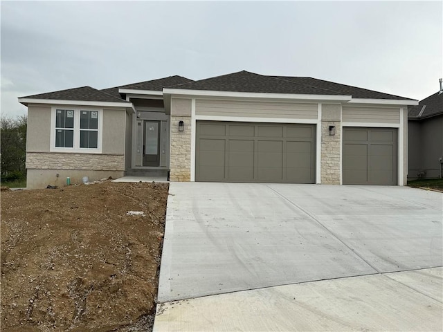 9845 104th St, Kansas City, MO 64157 - prairie-style house featuring a shingled roof, stucco siding, an attached garage, driveway, and stone siding