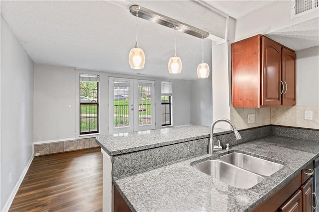 4727 Jarboe St Unit 52, Kansas City, MO 64112 - kitchen featuring a sink, dark wood finished floors, a peninsula, decorative light fixtures, and dark stone counters