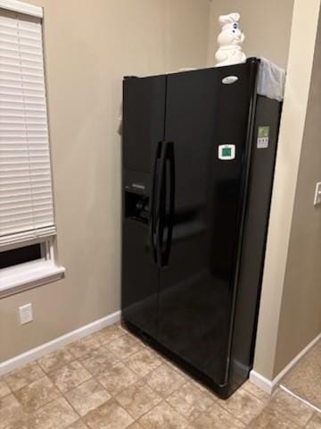 room details featuring black refrigerator with ice dispenser and baseboards