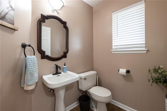 half bath featuring toilet and baseboards