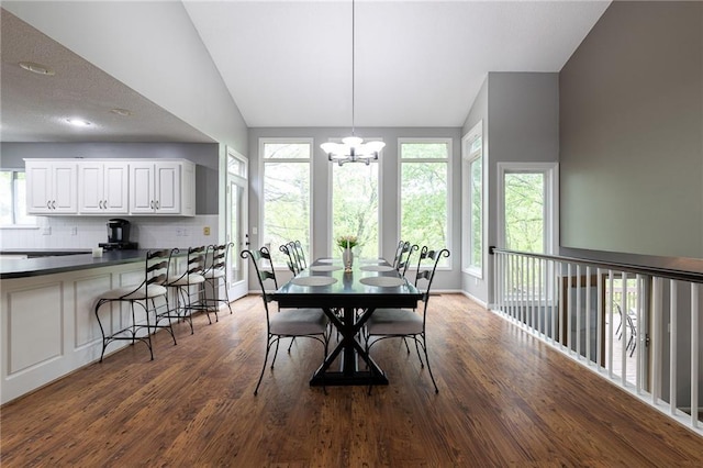 dining space featuring baseboards, a chandelier, wood finished floors, and vaulted ceiling