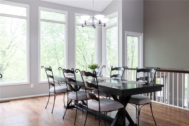 dining room featuring visible vents, wood finished floors, lofted ceiling, baseboards, and a chandelier