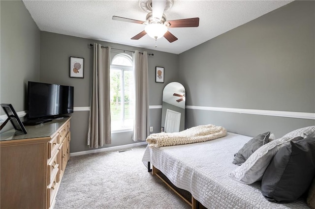 bedroom featuring a textured ceiling, baseboards, visible vents, and light carpet