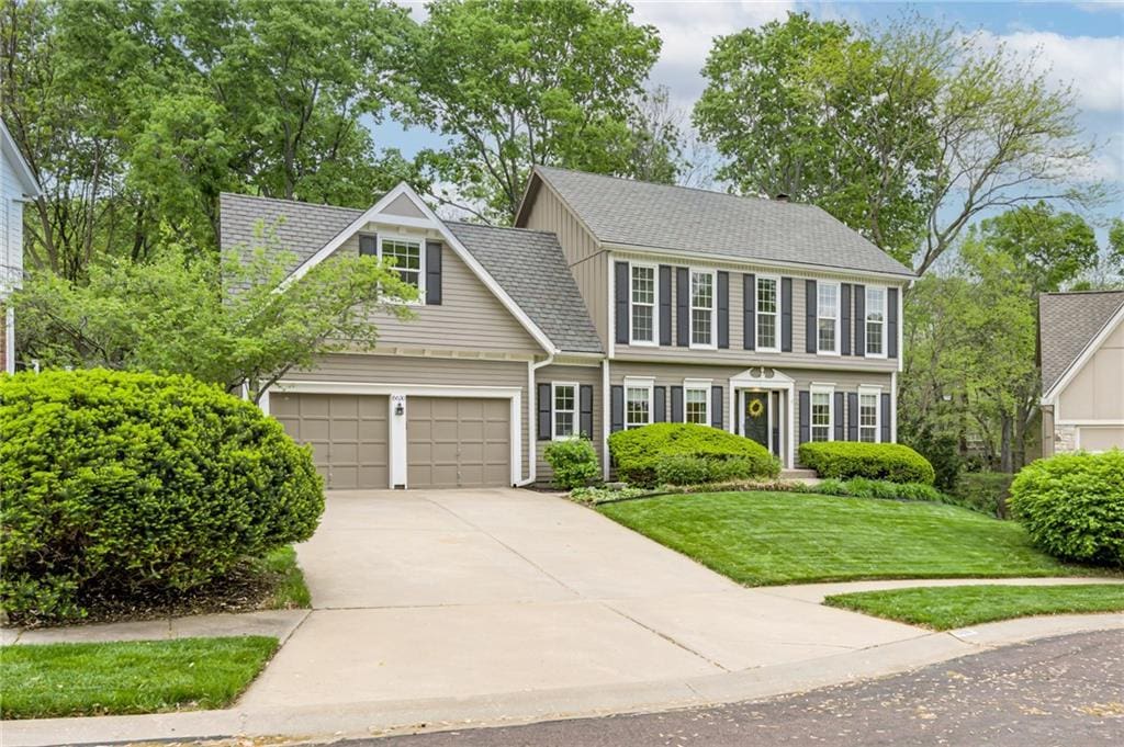 view of front facade with an attached garage, a shingled roof, driveway, and a front yard