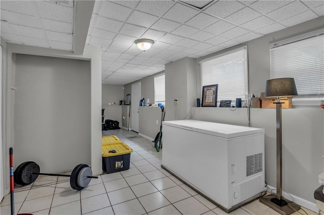 clothes washing area featuring baseboards and light tile patterned flooring