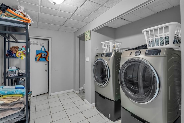laundry area with baseboards, washing machine and clothes dryer, light tile patterned floors, and laundry area