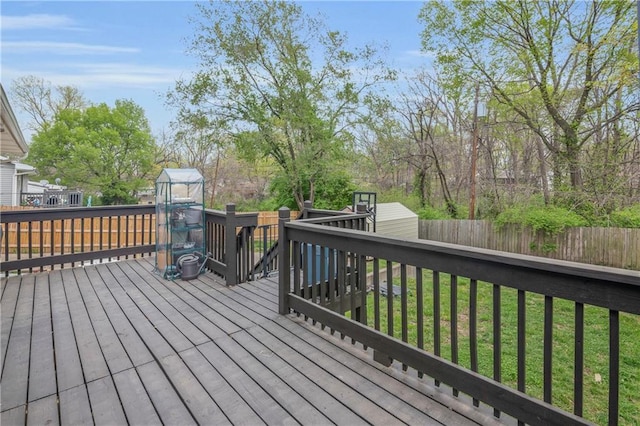 wooden deck with an outdoor structure, a storage unit, a fenced backyard, and a yard