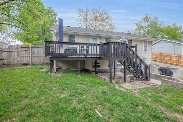rear view of house with a fenced backyard, a lawn, stairway, a deck, and a patio