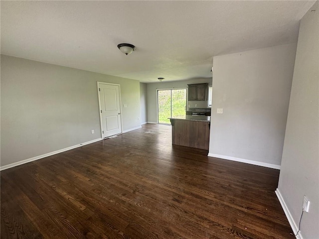empty room featuring baseboards and dark wood-style floors