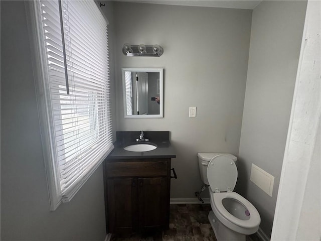 bathroom with toilet, vanity, and baseboards