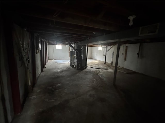 below grade area with water heater, heating unit, and visible vents