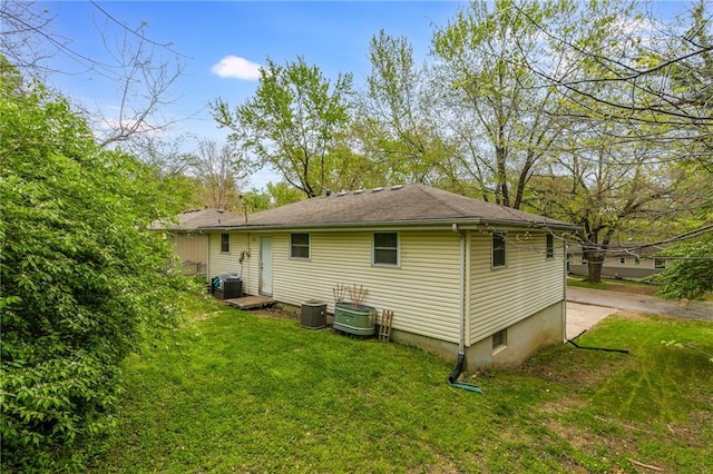 back of property with central AC unit and a lawn