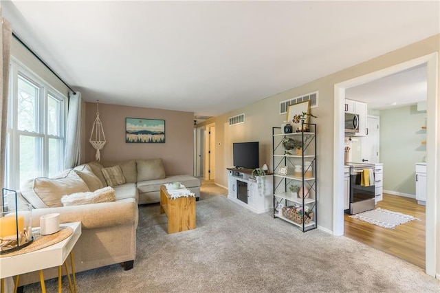living area featuring baseboards, visible vents, light carpet, and a fireplace