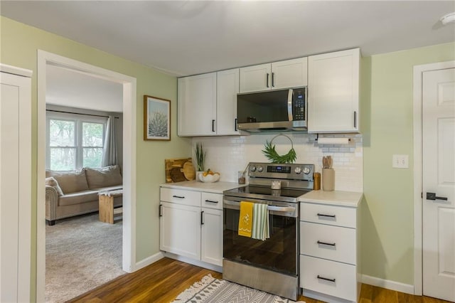kitchen featuring white cabinetry, stainless steel appliances, light countertops, dark wood finished floors, and backsplash