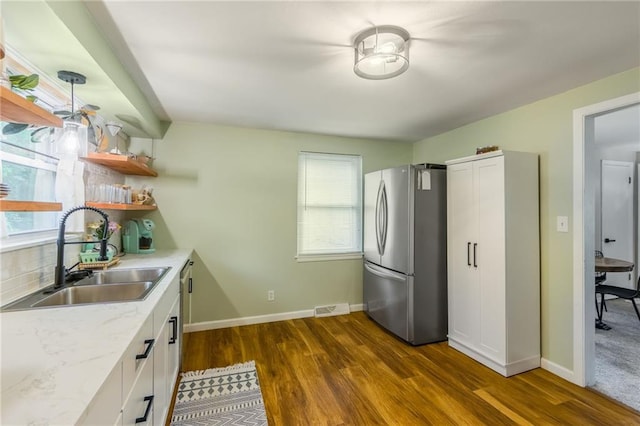 kitchen featuring a sink, dark wood-type flooring, visible vents, white cabinetry, and freestanding refrigerator