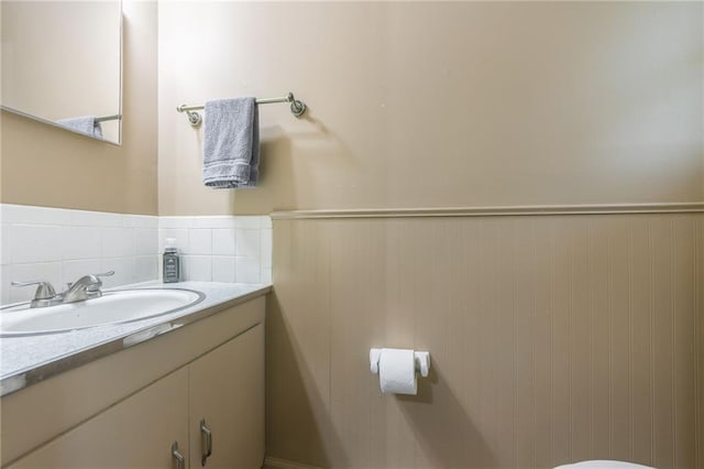 half bath with a wainscoted wall and vanity