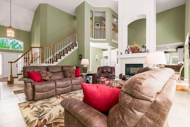 5720 NE Quartz Dr, Lees Summit, MO 64064 - living room featuring tile patterned flooring, a glass covered fireplace, high vaulted ceiling, stairway, and a chandelier
